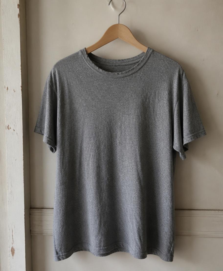 Camiseta de algodón gris jaspeada ligeramente usada en una percha de madera